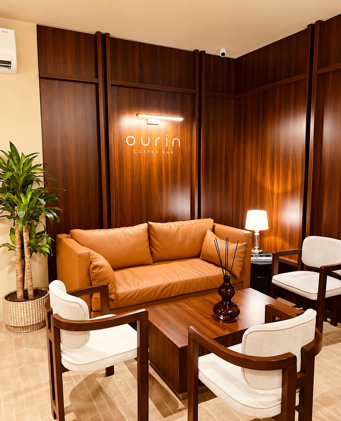 The wood-lined lounge at Ourin Coffee Bar, with the lit ourin sign above the caramel leather sofa